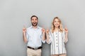 Photo of nice couple in casual clothing smiling while pointing fingers at copyspace Royalty Free Stock Photo