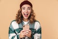 Photo of nice excited woman in knit hat smiling and using cellphone