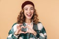 Photo of nice funny woman in knit hat smiling and gesturing heart sign