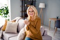 Photo of nice positive charming mature lady sitting sofa drinking warm natural tea enjoying small relax rest morning Royalty Free Stock Photo