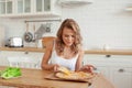 Photo of nice woman enjoys delicious slice of pizza, has good appetite, dressed in casual white shirt at home. Hungry woman indoor