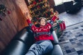 Photo of nice young pretty girl lying leather couch hands up wake up dreamy sleeping good morning winter hotel xmas tree