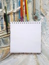 Photo of notepad against the background of a relief wall with color pencils and other decorative elements
