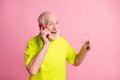 Photo of old cheerful positive man hold glasses wear lime t-shirt talk speak phone isolated on pink color background