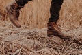 Photo of old males shoes. Man in brown trousers and boots being in motion on stones with stubble. Muddy footwear. Wide step Royalty Free Stock Photo