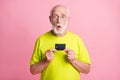 Photo of old shocked surprised grandfather wear lime t-shirt hold credit card isolated on pink color background