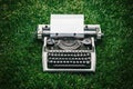 Photo of old typewriter on a green grass with a sheet of paper. Royalty Free Stock Photo