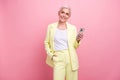 Photo of old woman business sales manager in yellow suit using cell phone look empty space app store isolated on pink Royalty Free Stock Photo