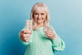 Photo of old woman give pills water glass isolated over blue background Royalty Free Stock Photo