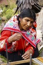 Old woman in Peruvian costume weaving alpaca sweater