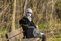 Photo of an older woman with a protective FFP2 or FFP3 N95 or N99 mask with a filter sitting in a park enjoying the warm day