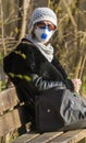 Photo of an older woman with a protective FFP2 or FFP3 N95 or N99 mask with a filter sitting in a park enjoying the warm day