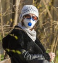 Photo of an older woman with a protective FFP2 or FFP3 N95 or N99 mask with a filter sitting in a park enjoying the warm day