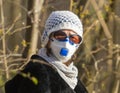 Photo of an older woman with a protective FFP2 or FFP3 N95 or N99 mask with a filter sitting in a park enjoying the warm day