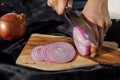 Photo of the onion slicing process. A woman cuts onions into circles with a knife