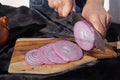 Photo of the onion slicing process. A woman cuts onions into circles with a knife
