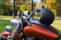 Photo of an open 3/4 black retro helmet, stand on the tank of the classic orange motorcycle. Motorcycle has lots of chrome details