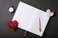 Photo of open empty journal with clock and crafty hearts over black table