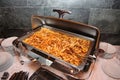 Photo of open steel Bain Marie on stand with a dish of Italian cuisine - pasta with tomato Basil and minced beef meat