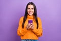 Photo of optimist good mood pretty woman brunette hair wear stylish orange sweater hold phone enjoy apple gadgets