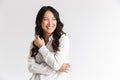 Photo of optimistic asian woman with long dark hair looking aside at copyspace and laughing, isolated over white background in st