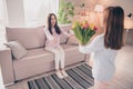 Photo of optimistic brunette red hairdo mom daughter gift flower sit on sofa wear sweater pants at home