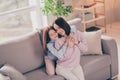 Photo of optimistic brunette red hairdo mom daughter hug closed eyes on sofa wear sweater at home Royalty Free Stock Photo