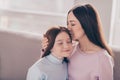 Photo of optimistic brunette red hairdo mom daughter hug kiss on sofa wear sweater at home Royalty Free Stock Photo