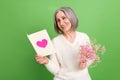 Photo of optimistic good mood smiling senior lady hold reading her greeting card happy valentine day isolated on green Royalty Free Stock Photo