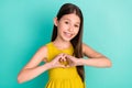 Photo of optimistic nice brown hair girl show heart wear yellow dress isolated on bright teal color background Royalty Free Stock Photo