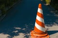 Photo Orange and white street cone against natural background, caution symbol