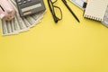 Photo overhead of moneybox calculator money pen glasses notebook and keyboard isolated on the yellow background