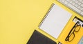 Photo overhead of notebook glasses paperclips clipboard keyboard and folder isolated on the yellow background Royalty Free Stock Photo