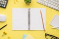 Photo overhead of notebook keyboard calculator pen pencil computer mouse notes plant glasses and paperclips isolated on the yellow Royalty Free Stock Photo