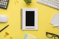 Photo overhead of notebook keyboard calculator pen phone computer mouse notes plant glasses and paperclips isolated on the yellow Royalty Free Stock Photo