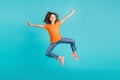 Photo of overjoyed cheerful girl wear trendy orange clothes have fun jump up open hnds hug cudle isolated on cyan color