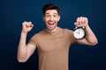 Photo of overjoyed cheerful man showing fist hand alarm clock rejoicing morning weekend holidy  on dark blue Royalty Free Stock Photo