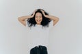 Photo of overjoyed curly haired woman laughs happily, has fun, dressed in white t shirt and jeans, smiles broadly, isolated over