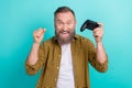 Photo of overjoyed funny gamer mature man grey beard fist up hold gamepad final boss victory console playstation