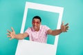 Photo of overjoyed guy dressed print polo in heart shape glasses stretching arms to you from frame isolated on teal Royalty Free Stock Photo