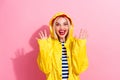 Photo of overjoyed lovely girl wear yellow waterproof clothes raise hands celebrate autumn holidays isolated on pink