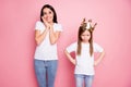 Photo of overjoyed obsessed funny mommy watch little angry spoiled daughter with crown on head impressed wear casual t