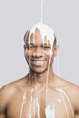 Paint falling on shirtless young Hispanic man`s head against gray background