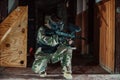 Photo of paintball player in goggle mask and camouflage aiming by paintball gun. Selective focus Royalty Free Stock Photo