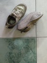 photo of a pair of dirty cloth shoes on a tiled floor