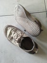 photo of a pair of dirty cloth shoes on a tiled floor