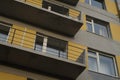 Photo of part of the building`s facade. Balconies, metal railings, and Windows form linear patterns.