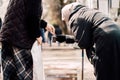 Photo of passerby givining alms for old hungry homeless female beggar on street