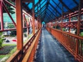 photo of a pedestrian bridge, long hallway, with orange railings and a blue roof in the buffer city of Jakarta