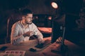 Photo of pensive interested man of business holding cup of hot coffeine beverage wearing spectacles looking into screen